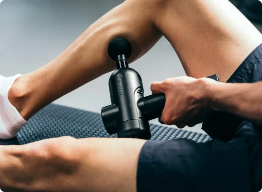 Foto de pistola de massagem sendo usada na panturrilha